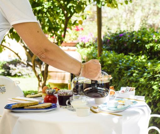 Colazione all'aperto con caffè, pane e natura rigogliosa.