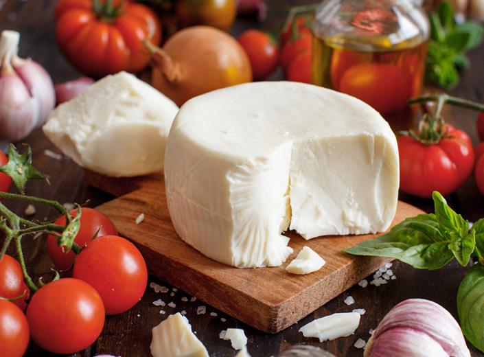 Formaggio su tagliere con pomodori, basilico e aglio.